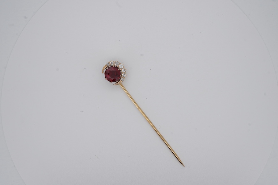 An early to mid 20th century yellow metal and single stone garnet topped doublet set stick pin, with diamond set crescent border, 61mm, gross weight 2.9 grams. Condition - fair to good